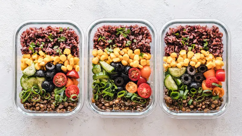 Refeições organizadas em recipientes de vidro com legumes, grãos e verduras.